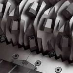 which are integral components in machinery for transferring torque and motion. The perspective is somewhat artistic, focusing on the interlocking teeth of the gears. The color palette is monochromatic, with various shades of gray, giving the image a metallic feel. This might be a part of a larger machinery, a close-up on a watch mechanism, or an abstract art piece inspired by mechanical elements.