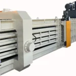 a large industrial baler, designed for full automatic operation with a capacity of 100 tons. This machinery is typically used for compressing waste materials into compact bales, which simplifies handling and transportation. The baler shown in the image is predominantly gray with white and orange accents, and it includes multiple compression chambers and hydraulic mechanisms to ensure efficient baling of materials. This type of equipment is crucial in waste management and recycling facilities to reduce the volume of waste and improve the efficiency of recycling processes.