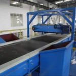 Průmyslový magnetický separátor v provozu na dopravním pásu, používaný k odstraňování železných materiálů v recyklačních a těžebních procesech.